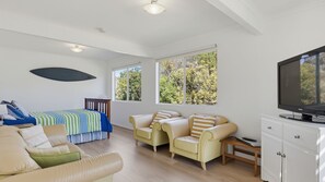 Um quarto amplo com uma cama, duas poltronas, um sofá, uma televisão e um armário.