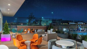 An outdoor seating area with modern furniture, a pool, and a night sky view. - Aloft by Marriott Denver North Westminster (Westminster)