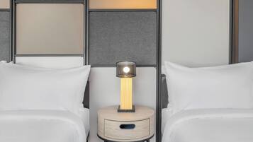 Un dormitorio con dos camas, una mesita de noche con lámpara y un panel en la pared.