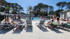 A poolside area with lounge chairs, a swimming pool, and trees in the background.
