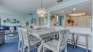 A dining area with a wooden table and chairs, a chandelier, and artwork on the walls.