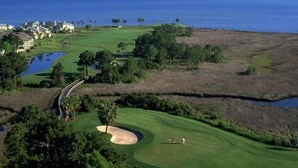A golf course with a water hazard, sand bunkers, and a view of the ocean.