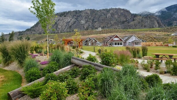 A residential area with houses, a wooden pergola, and a mountain backdrop. - OSOYOOS PRIVATE RESORT HOME STEPS FROM THE LAKE (Oliver)