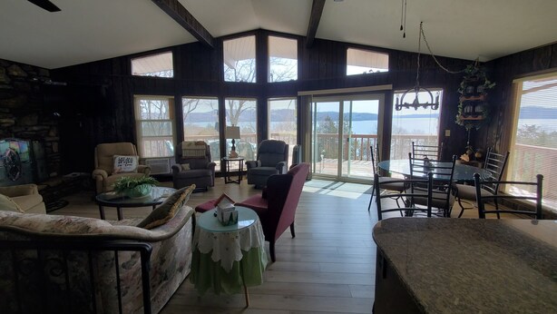 Un salón amplio con chimenea, asientos cómodos y ventanas grandes que ofrecen vistas al exterior.