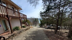 Una casa con balcón de madera, un sendero de piedra y vista a un lago.