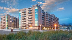 Een modern meerlaags hotel met balkons, gelegen nabij een waterkant.