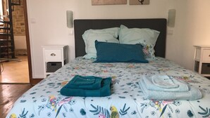 Une chambre à coucher avec un lit, des oreillers, une table de chevet et un mur décoré d’œuvres d’art.