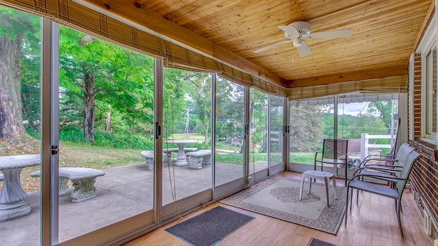 Un patio couvert avec des portes-fenêtres coulissantes, du mobilier d’extérieur et un ventilateur de plafond.