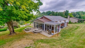 Une maison avec un patio couvert, un barbecue et un grand arbre.