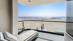 Un balcone con vista sulla spiaggia, un letto e un tavolo con sedie.