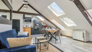 Un espace de vie de style loft comprenant un coin repas, une cuisine et une grande verrière.