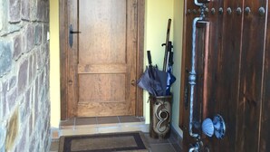 A wooden door with a metal handle, a stone wall, and a tiled floor.