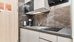 Een moderne keuken met een ingebouwde magnetron, koffiezetapparaat en een spoelbak.