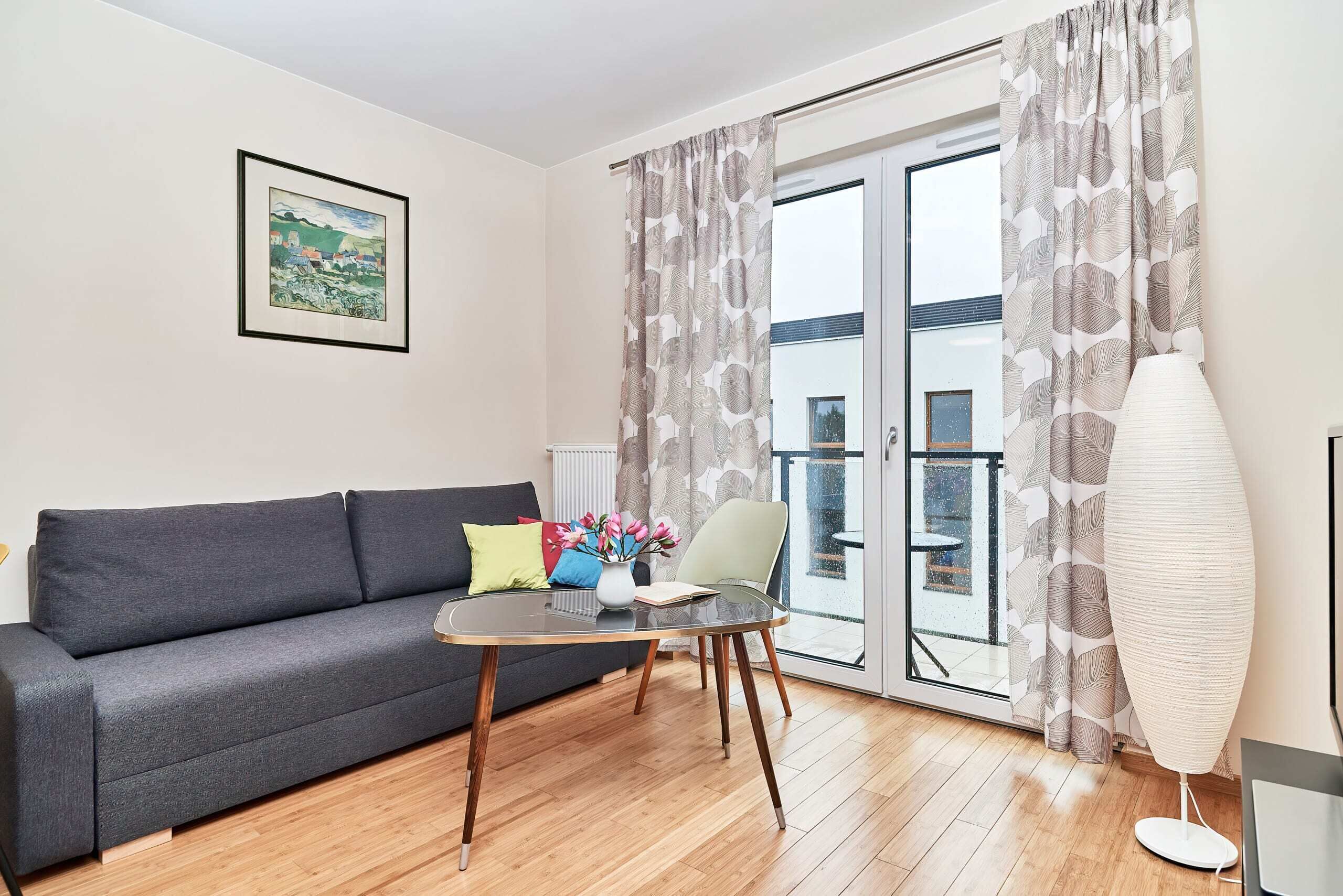 Living room with a sofa bed, TV and exit to balcony.