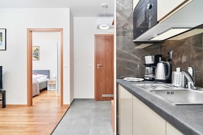 A modern kitchen with a sink, stove, and microwave.