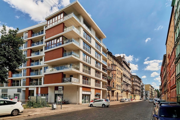 A multi-story building with balconies, a visible restaurant named 'GROSS,' and a street with parked cars.