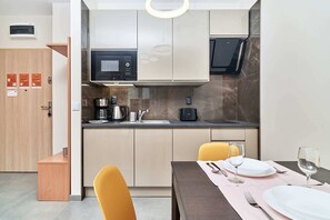 A modern kitchen with built-in appliances, a dining area with a table set for two, and a wooden door with informational cards.