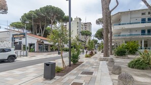 Una acera con un sendero pavimentado, un bote de basura y un edificio con un letrero que dice 'DOLLARO'.