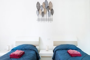 Ein Doppelbett mit blauer Bettwäsche und einem dekorativen Wandbild darüber.