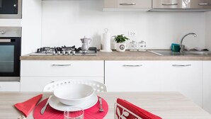 A modern kitchen with white cabinets, a gas stove, a coffee maker, and a sink.