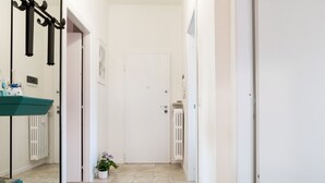 A hallway with a white door, a radiator, a potted plant, and a teal bench.