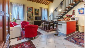 A spacious living area with a staircase, a dining table, and a kitchen area. - Ariostea University Duplex Apartment (Ferrara)
