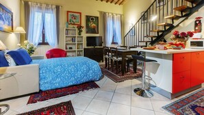 A cozy living room with a sofa, a dining area, and a kitchen. - Ariostea University Duplex Apartment (Ferrara)