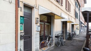 A narrow street with buildings on either side, a bicycle parked outside a shop, and a row of parked bicycles. - Ariostea University Duplex Apartment (Ferrara)