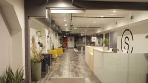 A modern office space with a reception desk, seating area, and plants. - Stay Classy Hostel (San Diego)