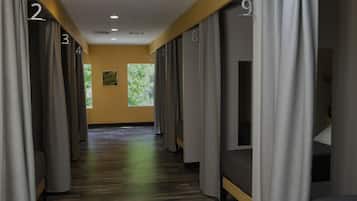 Pasillo de hotel con habitaciones numeradas, suelo de madera y amplias ventanas que dejan entrar luz natural.