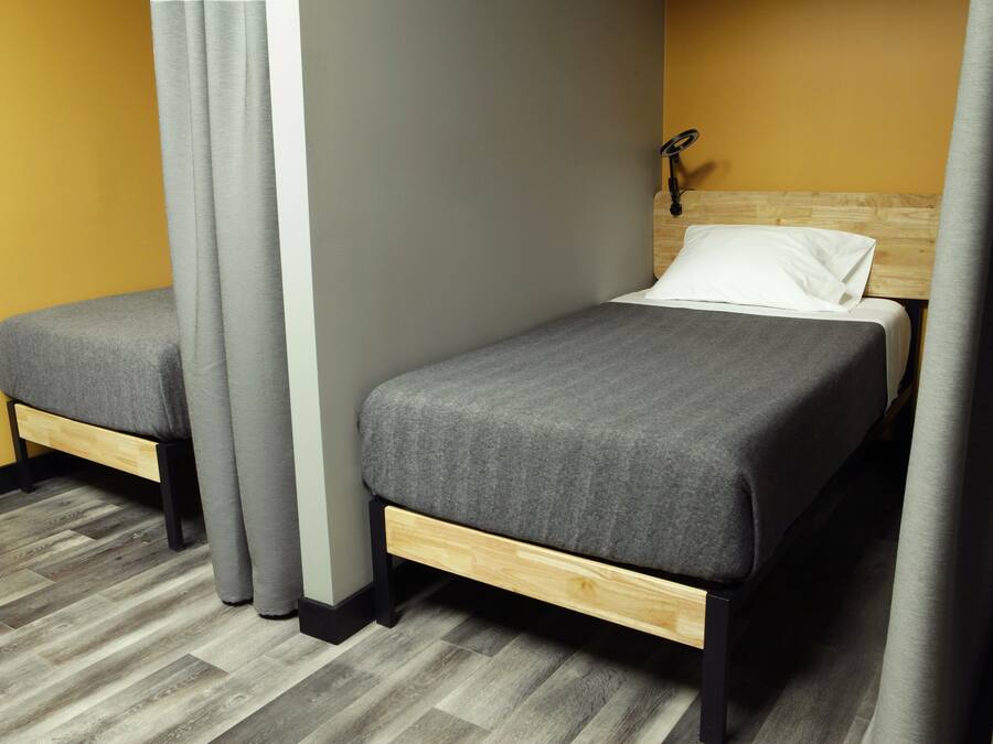 Quarto com uma cama, um banco e uma cabeceira.