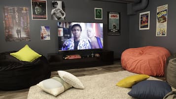 A living room with a television, bean bag, and posters on the wall.
