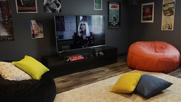 Un salon avec un téléviseur, un fauteuil poire et des affiches accrochées au mur.