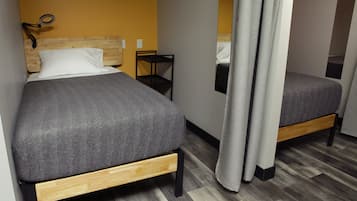 Un dormitorio con dos camas, cabeceros de madera, mesitas de noche y un espejo.