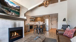 A modern living room with a fireplace, a dining area, and a kitchen with stainless steel appliances. - Steps to Shopping, Restaurants, Year-Round Recreation & More! Park City Resort Village 208 (Park City)