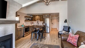 A modern kitchen with a dining area, a fireplace, and a living room with a sofa and a TV. - Steps to Shopping, Restaurants, Year-Round Recreation & More! Park City Resort Village 208 (Park City)