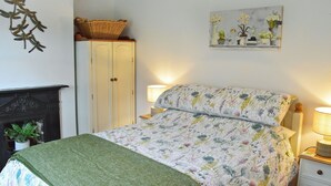 Une chambre à coucher comprenant un lit, une table de chevet, une lampe, une commode, une cheminée et un élément décoratif mural.