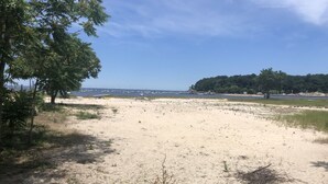 A beach with two sun loungers and a small table, surrounded by sand and sparse vegetation. - Beachfront Summer Rental- Sea Cliff (Sea Cliff)