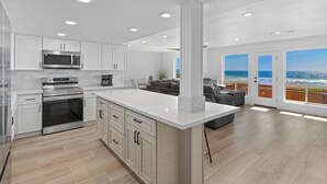 A modern kitchen with white cabinetry, stainless steel appliances, and a large island. - Direct Oceanfront 2 Bedroom 2 Bathroom on the 1st Floor (Imperial Beach)