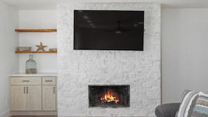 A living room with a fireplace, a flat-screen TV mounted above it, a sofa, and a coffee table. - Direct Oceanfront 2 Bedroom 2 Bathroom on the 1st Floor (Imperial Beach)