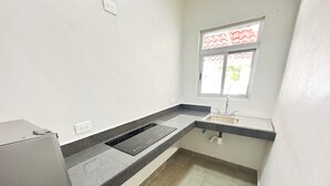 Una cocina con estufa integrada, un lavamanos y una ventana con persiana de diseño rojo y blanco.