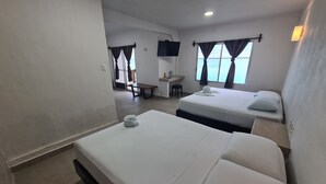 Habitación de hotel con dos camas, un escritorio, una silla, televisor y vista al mar.