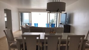 A dining area with a table and chairs, a television, and a view of the city. - Modern Oceanfront Hideaway, Ship Views & Steps to the Sand. Fort Lauderdale (Fort Lauderdale)