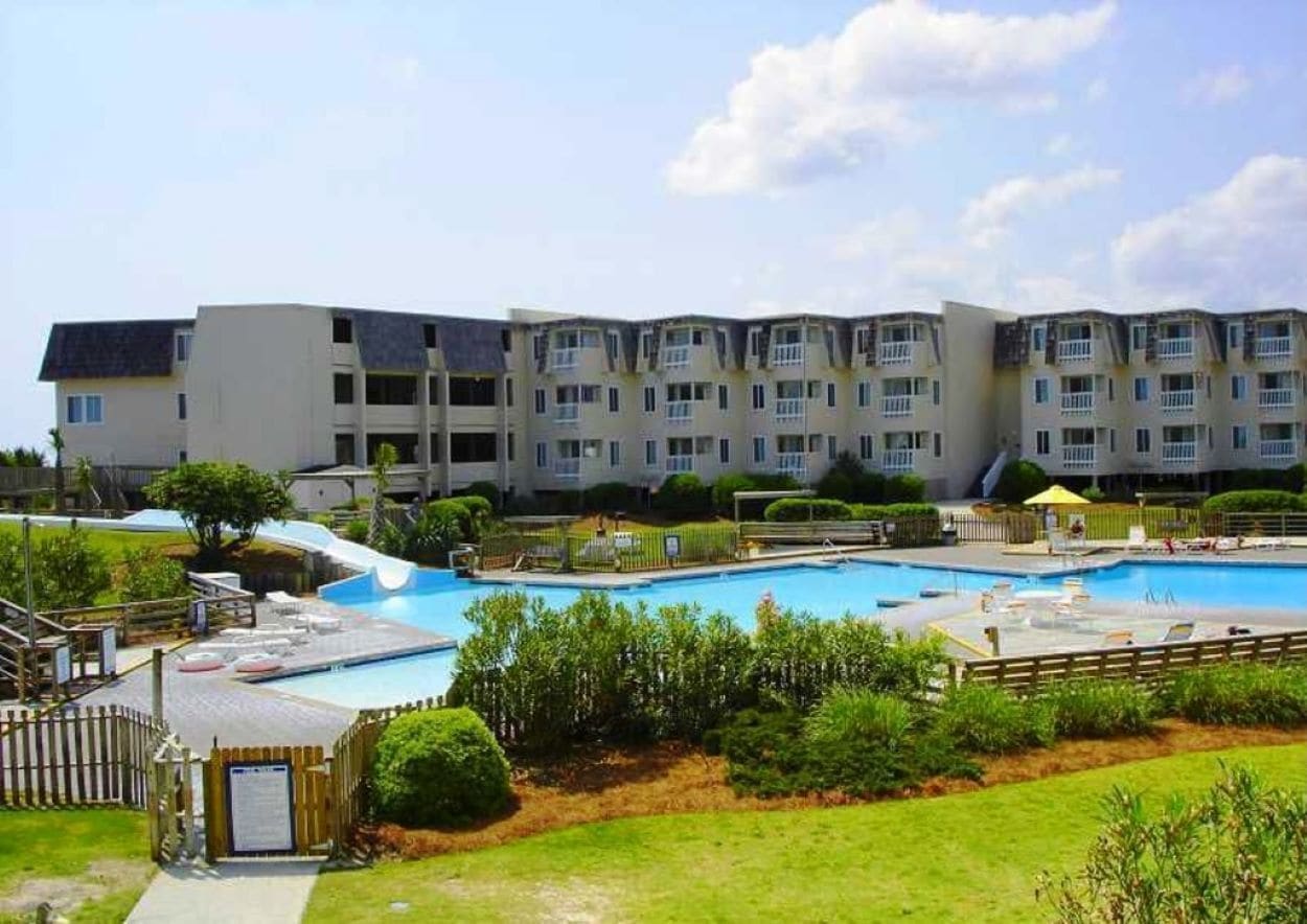 Un hotel con diverse altezze, una piscina e un'area giochi per bambini.