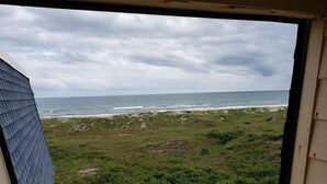 A view of the ocean from a window with a view of the beach and grassy area. - 2024 Totally Renovated Oceanview condo Indoor/Outdoor Pool, 150' Waterslide Wifi (Atlantic Beach)