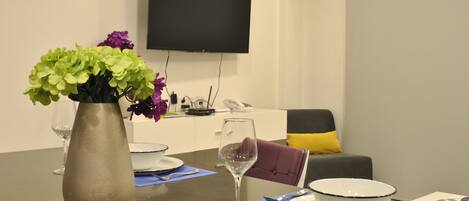 A dining table with a vase of flowers, a wine glass, and a bowl on a placemat.