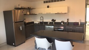 Une cuisine moderne dotée d’un îlot central, d’appareils électroménagers en acier inoxydable et de chaises blanches.