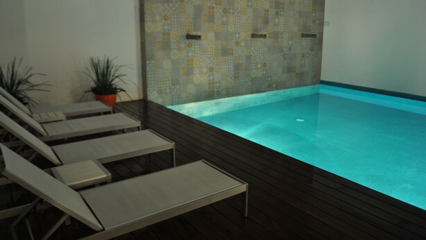 Une piscine avec des chaises longues et des plantes en pot.