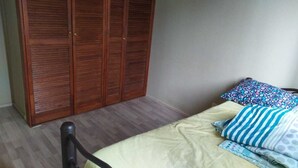 A bedroom with a bed, a wooden wardrobe, and a chair.
