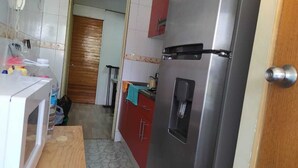 A compact kitchen with a refrigerator, microwave, and wooden countertop.